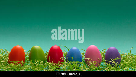 Easter eggs, pastel colors painted, standing in a row, green background, banner Stock Photo