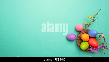 Easter eggs, pastel colors painted, in a decorated nest, green background, top view, copy space Stock Photo