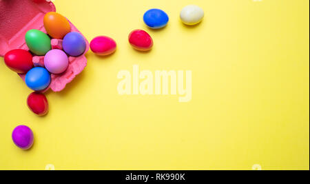 Easter eggs, pastel colors painted and a carton case, yellow background, copy space Stock Photo