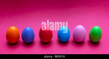 Easter eggs, pastel colors painted, standing in a row, bright pink background, banner Stock Photo