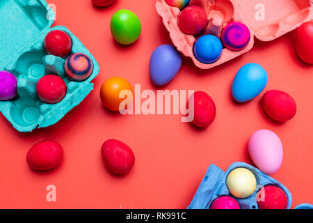 Easter eggs, pastel colors painted and a carton case, orange color background, top view Stock Photo