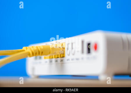 wireless internet router with connecting cables on blue background Stock Photo