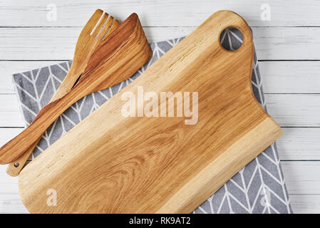 Kitchen utensils, cutting board, spatula and towel on white wooden background Stock Photo