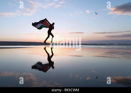Photo of youth man holding up Palestine flag near the beach. Gaza,Palestine Stock Photo