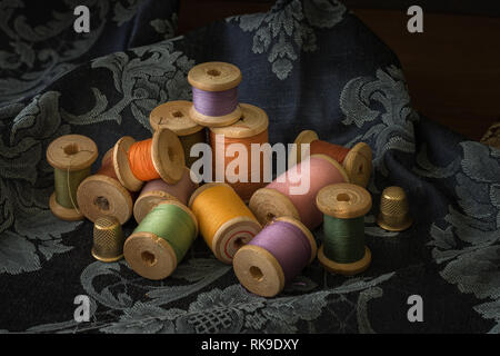 Bobbins with colorful threads on old wooden table background, Sewing background Stock Photo