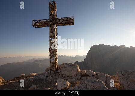 At sunrise, summit stone cross of the Sassopiatto mountain peak. Sassolungo mountain group. The Dolomites. Italian Alps. Europe. Stock Photo