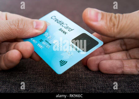 Credit card has built-in fingerprint scanner. Illustration of biometric payment security. One male hand is holding blue card and other touching scanne Stock Photo