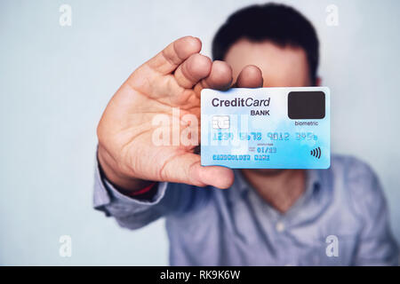 Concept of biometric verification on credit card. Cardholder showing payment card with finger sensor. Make purchase using fingerprint scanner technolo Stock Photo