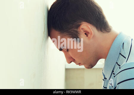 Depressed man his head against a wall. guy's banging his head against the wall. Boring guy into depression