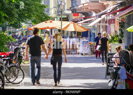 Couple walks hand-in-hand down charming pedestrian shopping street with outdoor cafes in Charlottenburg district, Berlin Germany Stock Photo