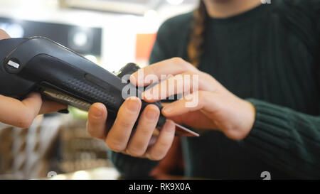 girl pays with a card in the terminal and enters a pin code Stock Photo