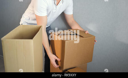 Young delivery service man carrying Boxes Into New Home On Moving Day Stock Photo