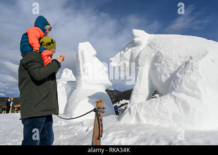 Bernau Im Schwarzwald, Germany. 10th Feb, 2019. At the third Black Forest Snow Sculpture Festival, a father and his child look at the works of art made of snow whose contours have been eroded by the wind or which have been thawed away by the mild temperatures. In the middle is the White Moai, on the right the piglet of the artist team Flavio Prinoth and Pierluigi Orler. Credit: Felix Kästle/dpa Credit: dpa picture alliance/Alamy Live News/dpa/Alamy Live News Stock Photo