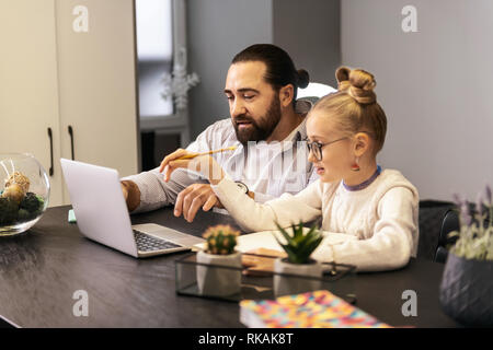 Dark-haired bearded teacher in a striped shirt doing home task with his pupil Stock Photo