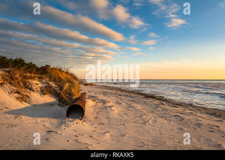 Big old rusty pipe on the sandy beach in sunset light. Hel Peninsula. Poland Stock Photo