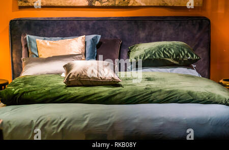 modern double bed with sheets and pillows in diverse colors, bedroom interior Stock Photo