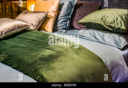 bed with sheets and pillows in diverse colors, modern bedroom interiors Stock Photo