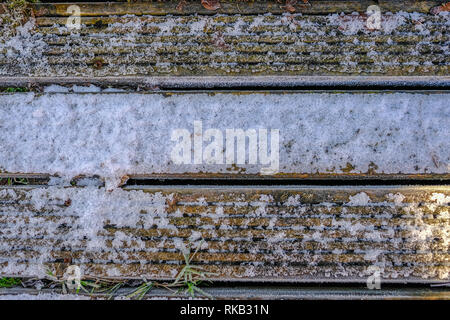 Three wooden decking planks covered with light snow and frost. Stock Photo