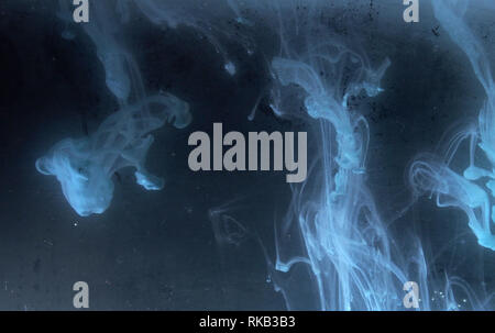 A drop of paint dissolves in water. On black background. Abstract figures. Stock Photo