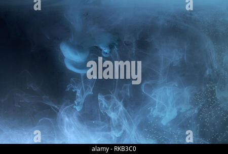 A drop of paint dissolves in water. On black background. Abstract figures. Stock Photo