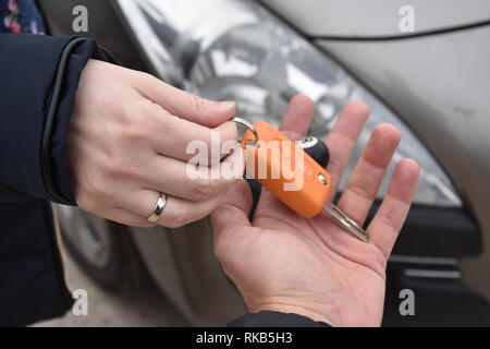 car sales. one person sells car and gives the key to the new owner - Image Stock Photo