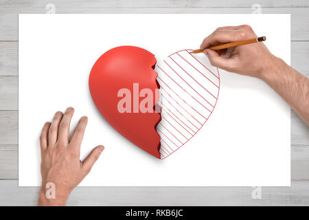 View from above of man's hands on a desk drawing with a pencil the second half of the broken red heart lying on a white sheet of paper. Stock Photo