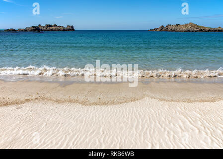 A gentle wave beaching on Saye Bay in Alderney, one of the two finest beaches for swimming and sunbathing. Stock Photo