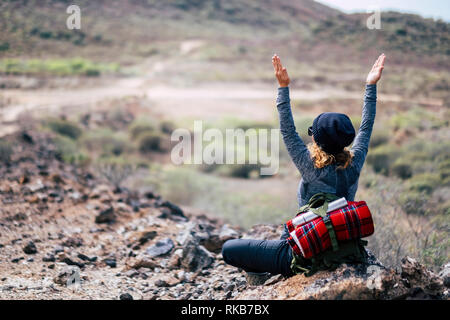 Rear view of woman with blonde curly hair doing yoga position and meditate during travel trekking hiking adventure activity - enjoying and feeling the Stock Photo