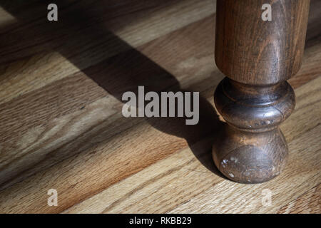 Wooden table leg casting shadow on oak hardwood floor Stock Photo