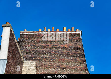 elevated old brick wall side of an of an apartment building with chimney stacks against a deep blue sky ,Paris , France Stock Photo