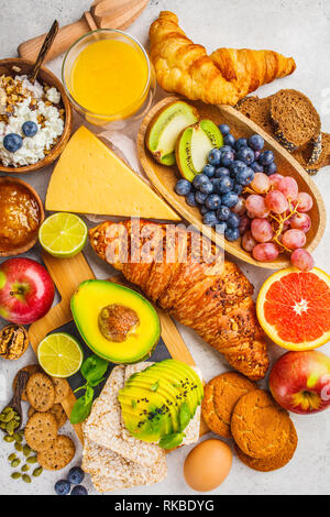 Healthy balanced breakfast on a white background. Muesli, juice, croissants, cheese, biscuits and fruit, top view. Stock Photo