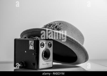 Black and white, interior close up of old 1950's Fedora/ trilby hat leaning on old, vintage Kodak Box Brownie camera (Model 1) of the same period. Stock Photo