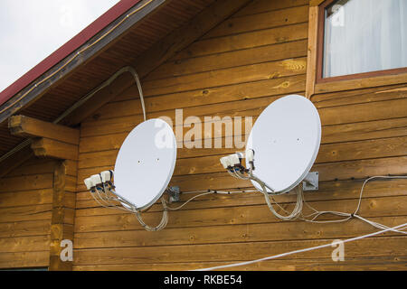Two satellite dishes attached to wooden wall of countryside house. Horizontal color photography. Stock Photo
