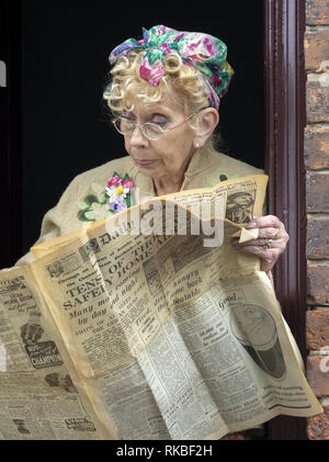 Woman dressed in period costume reading newspaper at the 1940's weekend at the Black Country Living Museum in Dudley, West Midlands, England, UK Stock Photo