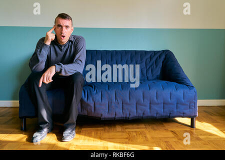 Handsome guy posing - angry and stressed man sitting on the sofa Stock Photo
