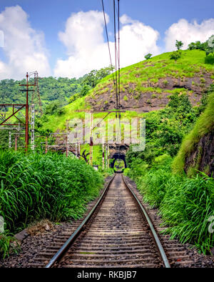 Railway line passing through a tunnel, surrounded by lush green countryside on Pune Mumbai route. Stock Photo