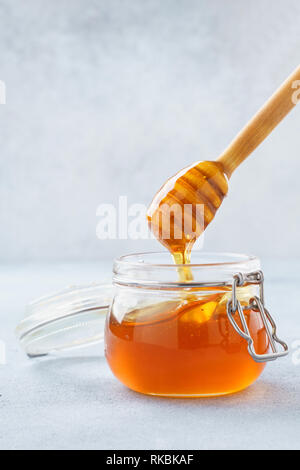 Honey dripping in a jar from wooden dipper. Stock Photo