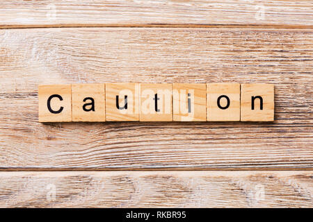 CAUTION word written on wood block. CAUTION text on wooden table for your desing, concept. Stock Photo