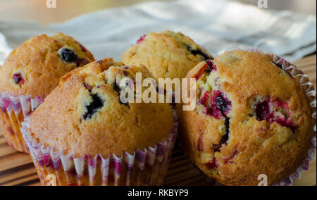 Muffins with red and black currant. paper bakeware with Valentine's day design with pink hearts. Close up, angle view Stock Photo