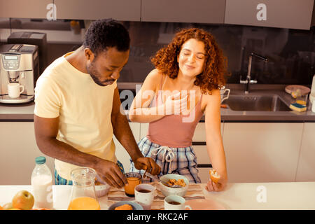 Slim curly wife laughing while listening to jokes of her husband Stock Photo