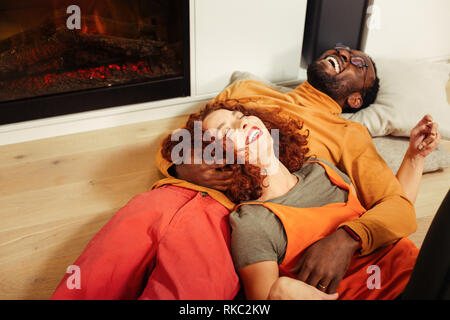 Young stylish couple lying on the floor near fireplace Stock Photo