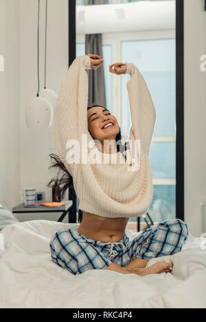 Woman wearing pajama trousers stretching and smiling Stock Photo