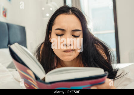 Woman feeling thoughtful while reading philosophical book Stock Photo