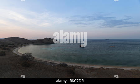 Cove at Pulau Lawalaut island with two boats moored inside as sunsets in south pacific Stock Photo