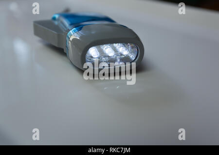 Dyno torch, dynamo wind up flashlight hand pressing crank, squeezing a handle (detail), mechanically powered three LED flashlight Stock Photo