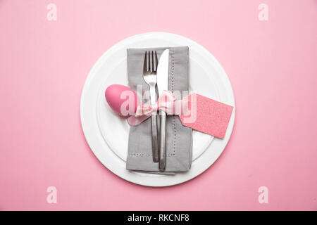 Easter table, place setting. Easter egg, pink color painted in a white plate, pink background, top view Stock Photo