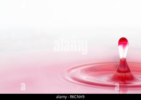 Close up of a water drop landing in pink water Stock Photo