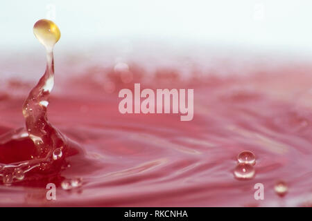 Close up of a water drop landing in pink water Stock Photo