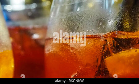 Alcoholic aperitif just served cold and with ice. The colors of the glasses are red and yellow and there are the traditional straws. Stock Photo