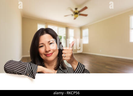 Hispanic Woman with Thumbs Up In Empty Room of House. Stock Photo